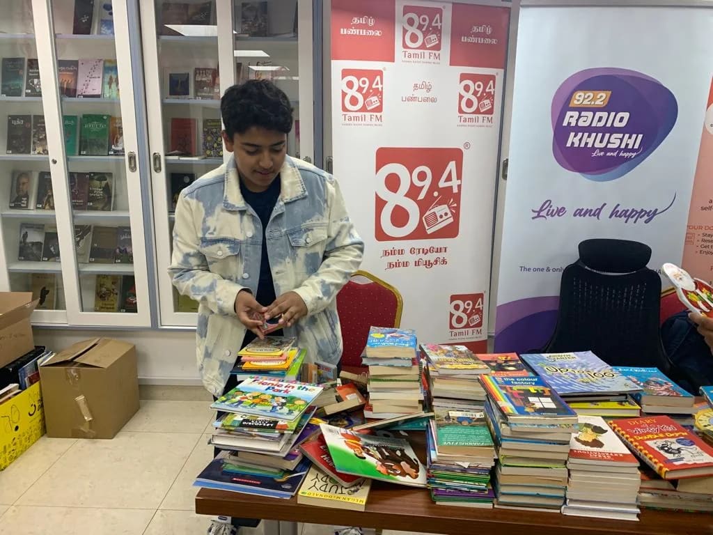 A volunteer arranges donated books on a table at the radio station.