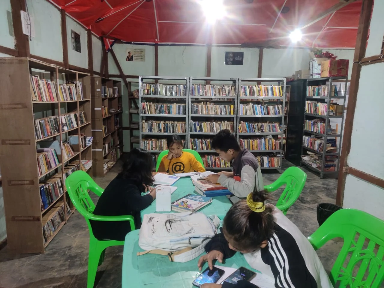 Children read around a table surrounded by library bookshelves.