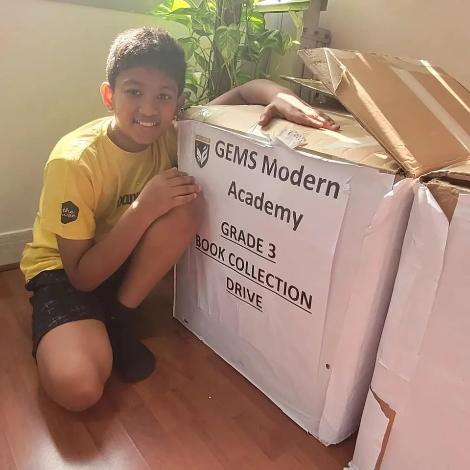 A young volunteer beside a labelled box of books