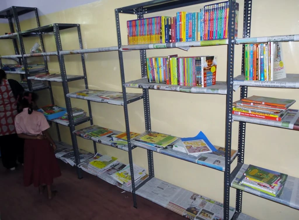 Books arranged on open shelves in a Velachery school